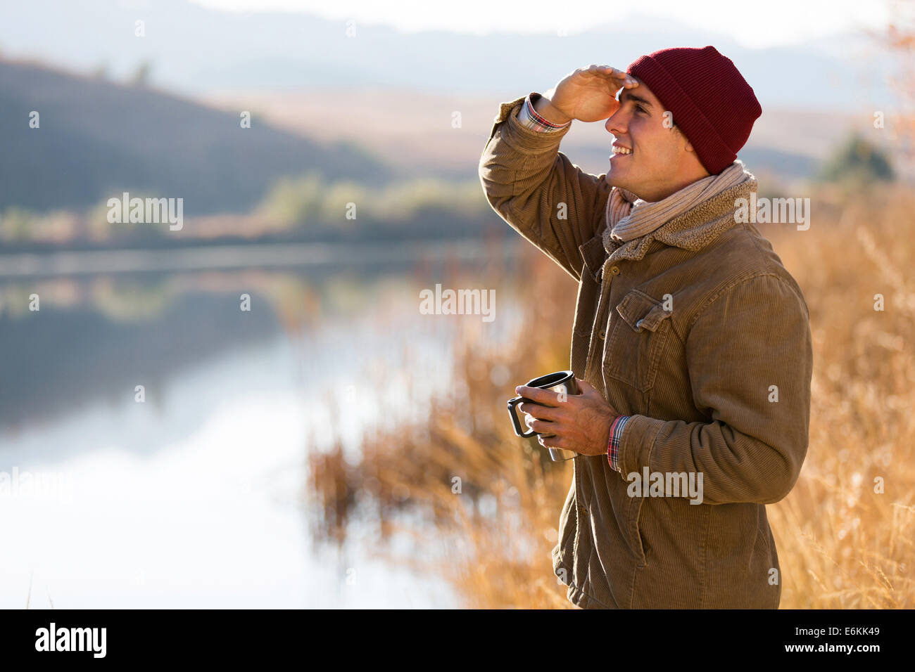 glücklich Jüngling Kaffeetasse halten und Blick in Ferne in Wintermorgen Stockfoto