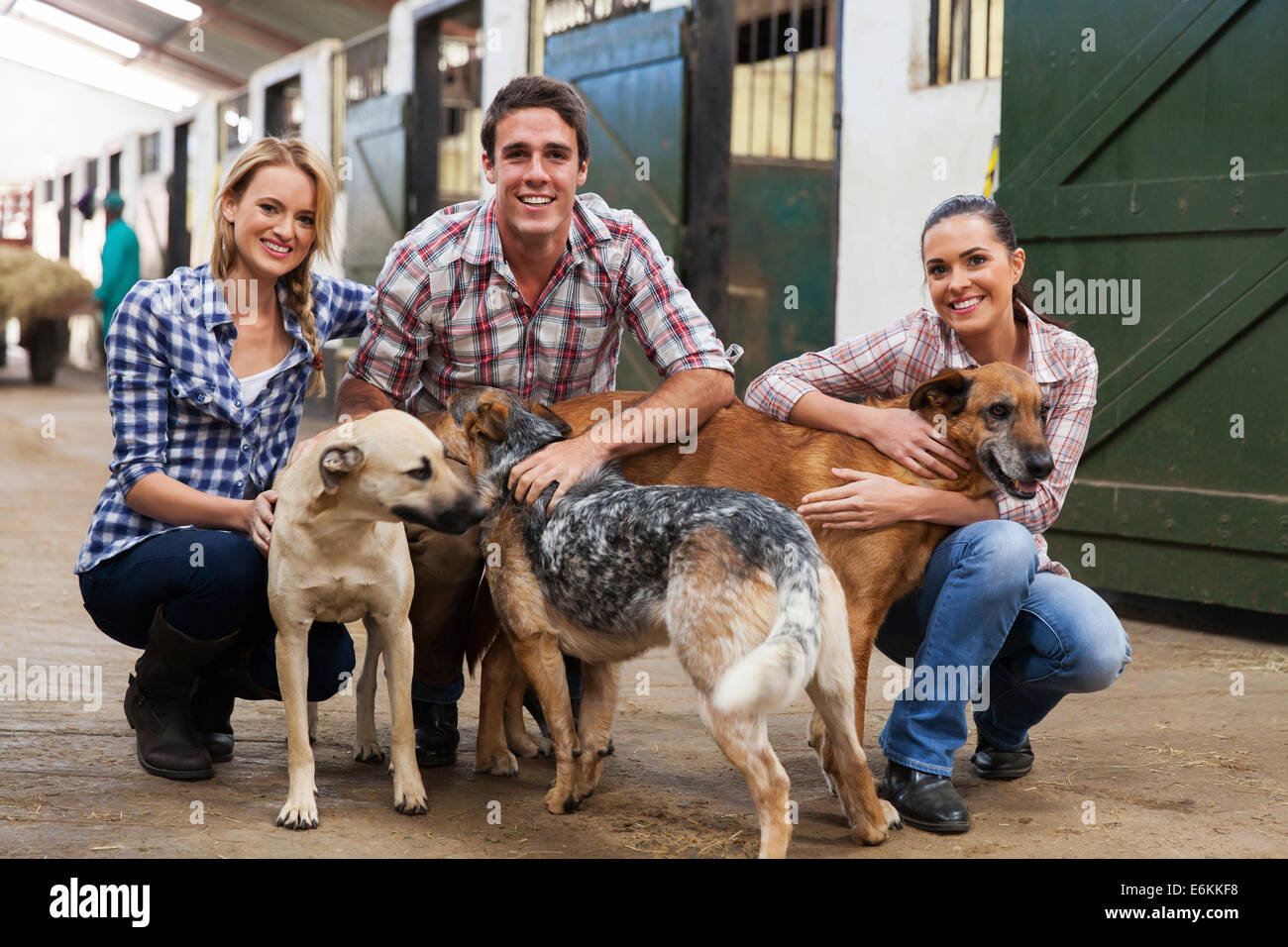 Gruppe von glücklich Landarbeiter mit Hunde in Ställen Stockfoto