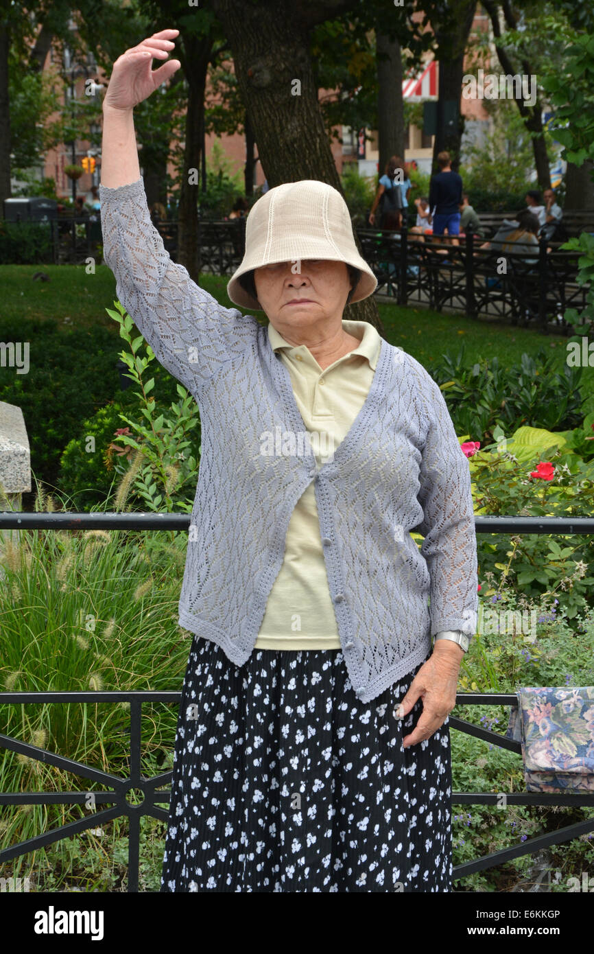 Eine ältere chinesische Frau Praktiken Falun Dafa Übungen in Union Square Park in New York City. Dies ist thh Falun ständigen Haltung. Stockfoto