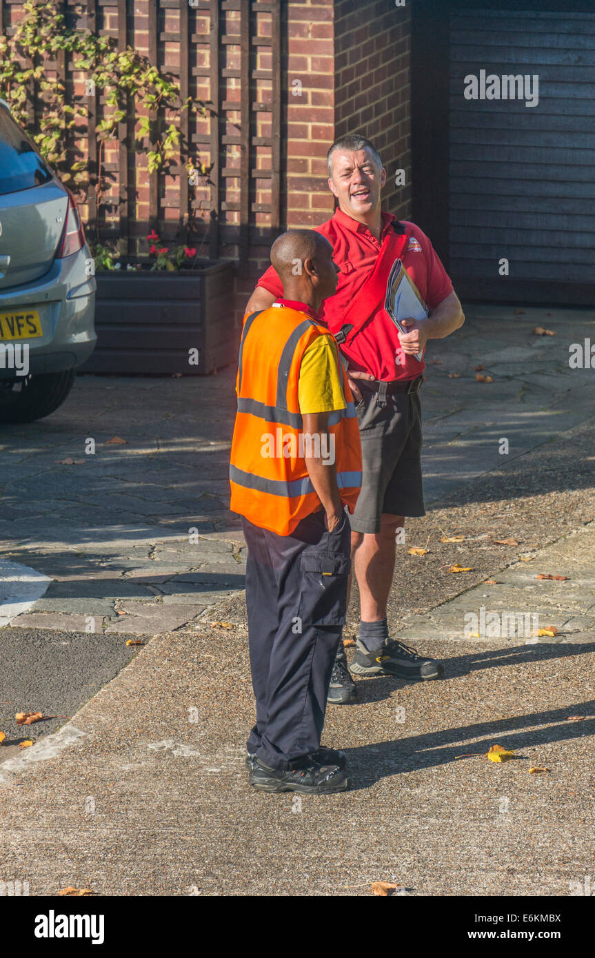 Ein Lieferwagen Fahrer Kurier Chatten zu einem glücklichen Postbote seine Post rund in Royal Mail Sommer Shorts uniform zu tun. Banstead, Surrey, England, UK. Stockfoto