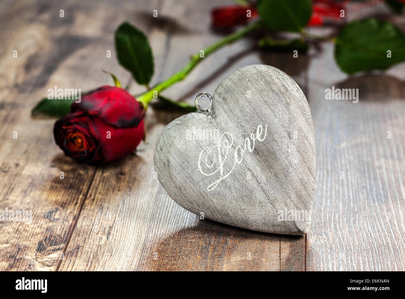 Valentinstag-Symbol. Herz auf einem hölzernen Hintergrund mit roten Rose. Stockfoto