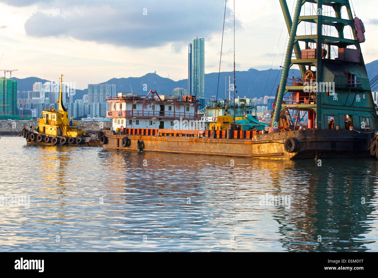 Schlepper bewegt sich ein Derrick Barge In der Causeway Bay Typhoon Shelter, Hong Kong. Stockfoto