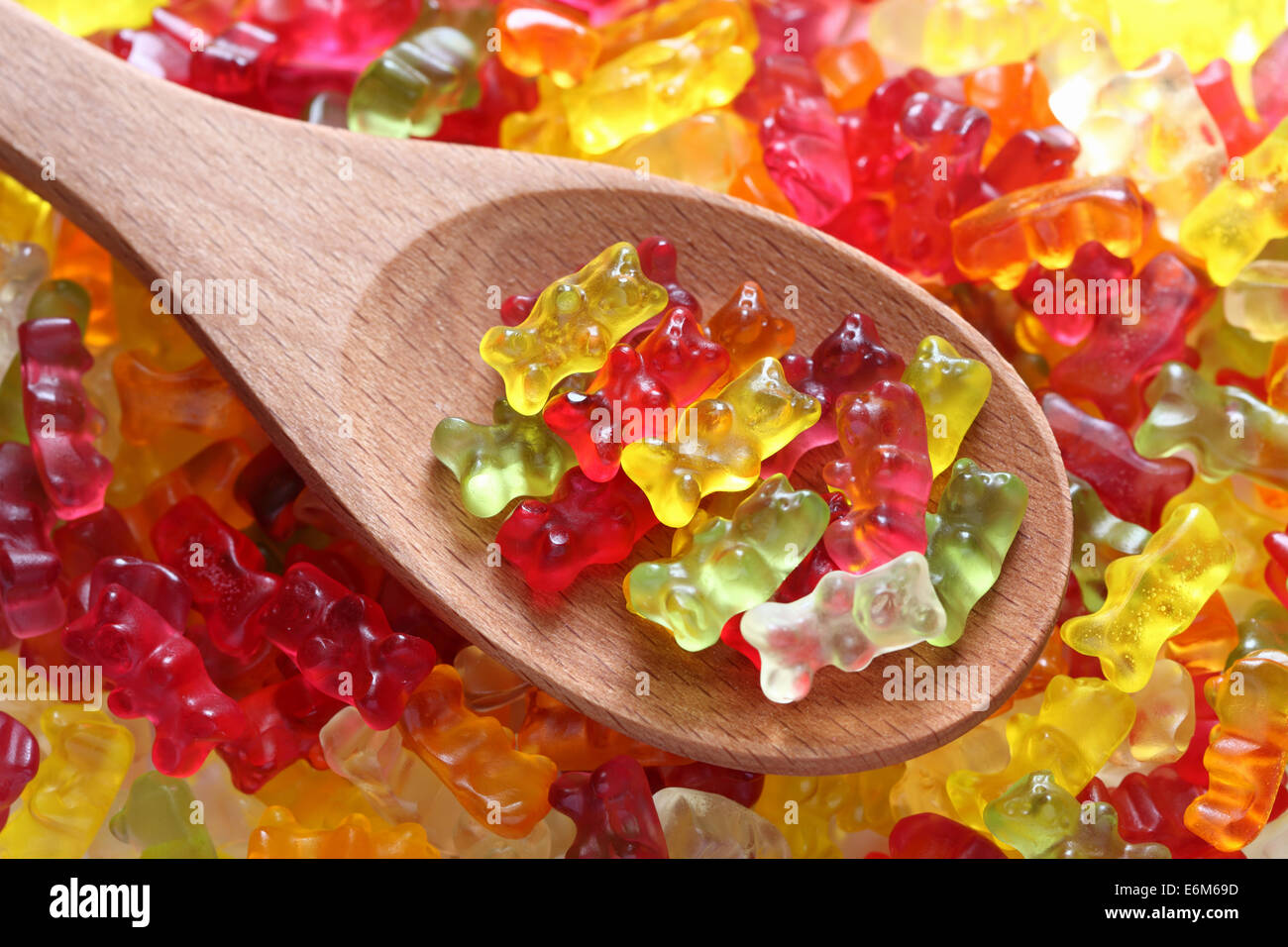 Gummibärchen auf einem Holzlöffel auf Gummibärchen Hintergrund. Closeup. Stockfoto