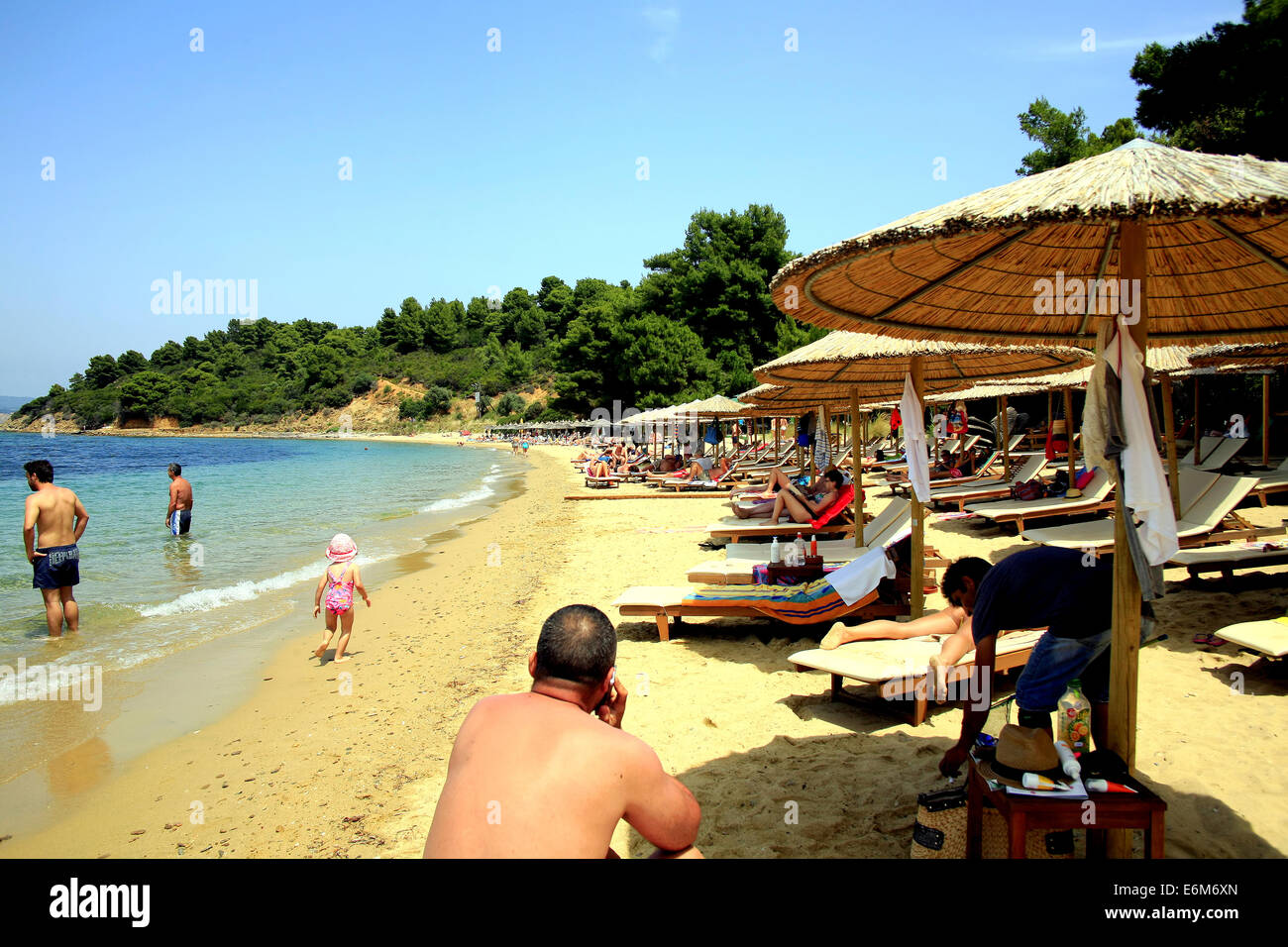 Familien genießen die Sonne, Meer und Sand am Strand von Agia Eleni auf der Insel Skiathos auf den griechischen Inseln, Griechenland. Stockfoto