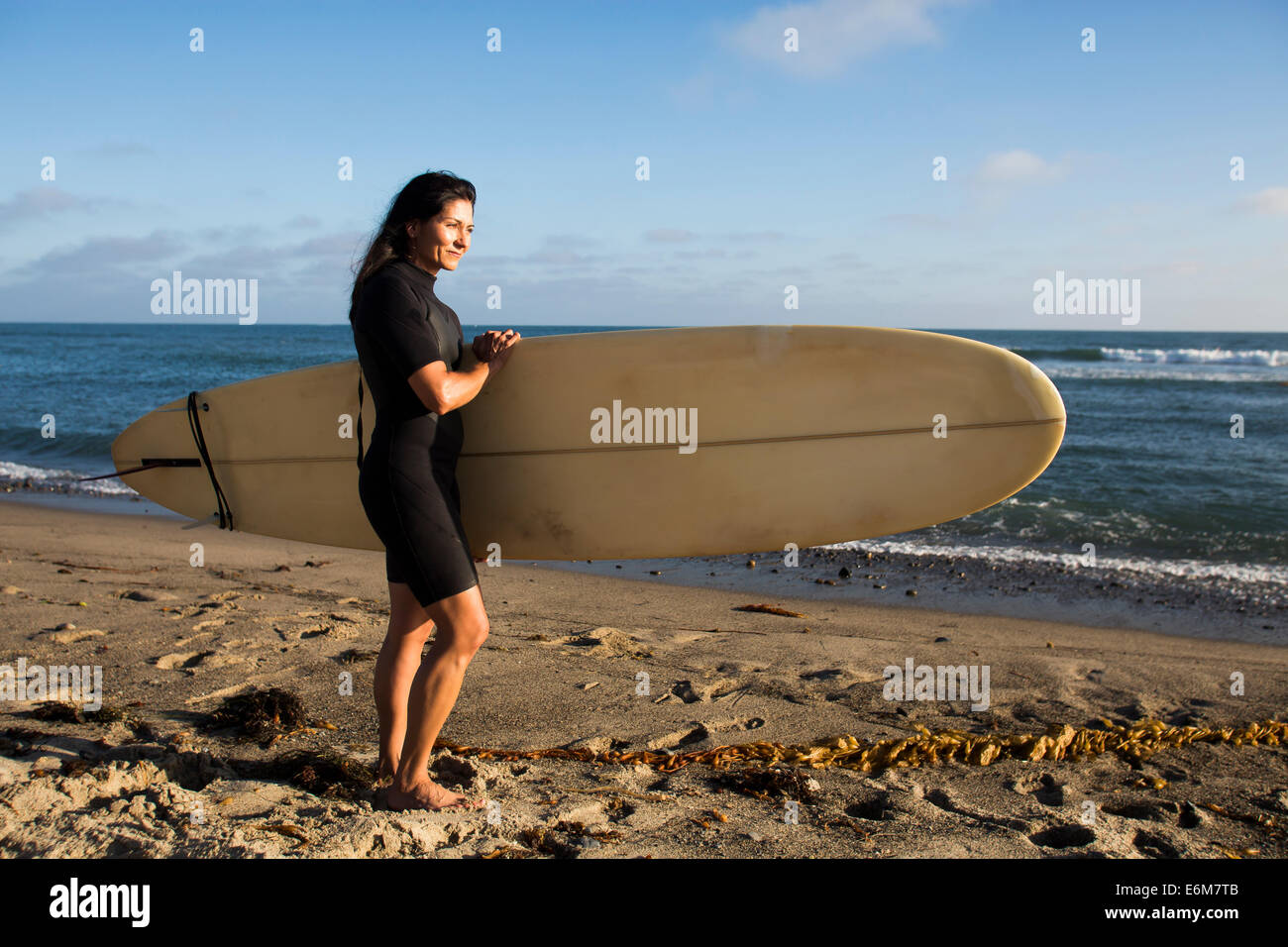 Frau Holding Surfbrett am Strand Stockfoto
