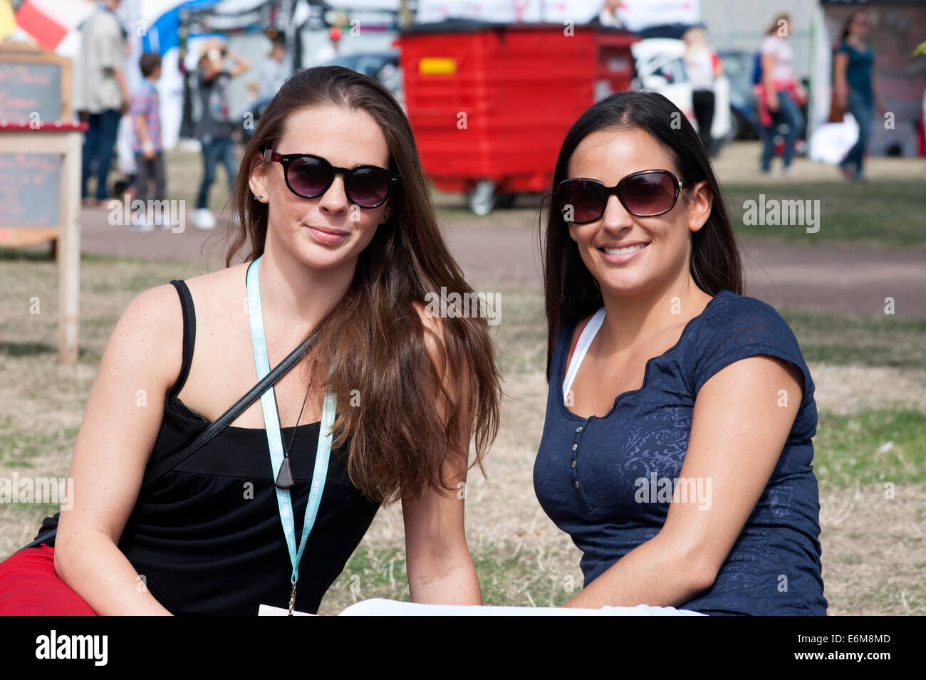 zwei hübsche junge Frauen genießen die Sonne und genießen Sie die Atmosphäre an der siegreichen Festival 2014 Southsea England uk Stockfoto