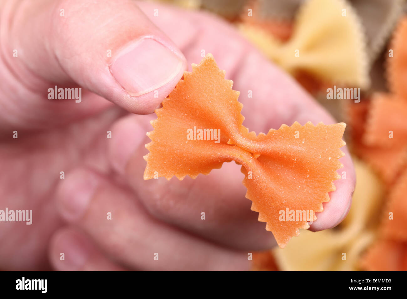 Rote Nudeln Farfalle in den Fingern über bunte Pasta Farfalle ...