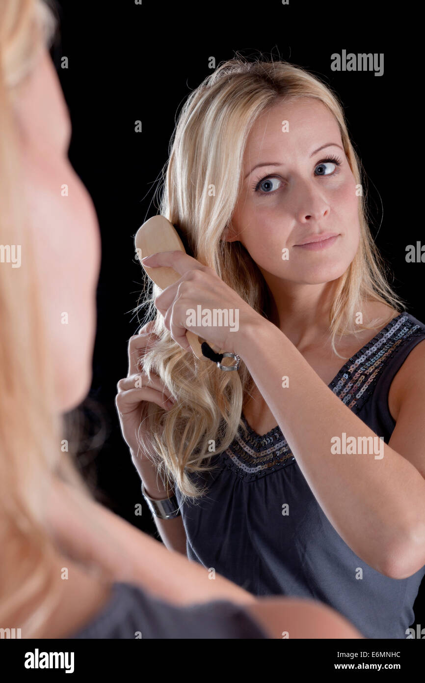 Junge Frau, Reflexion, ihr blondes Haar Bürsten Stockfoto