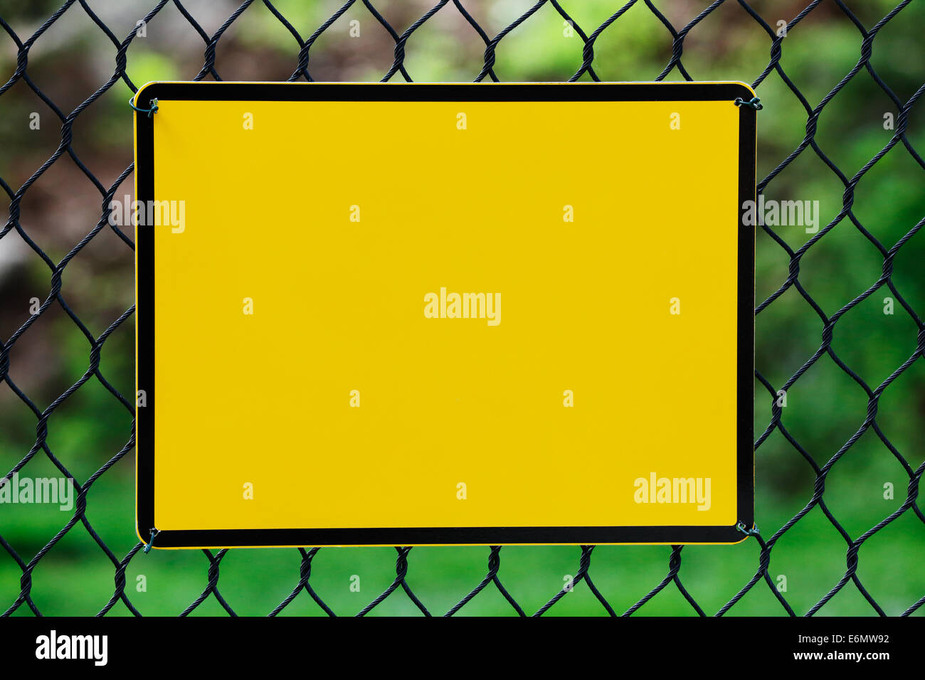 Leere gelbe Info-Platte hing an einem Drahtzaun Stockfoto