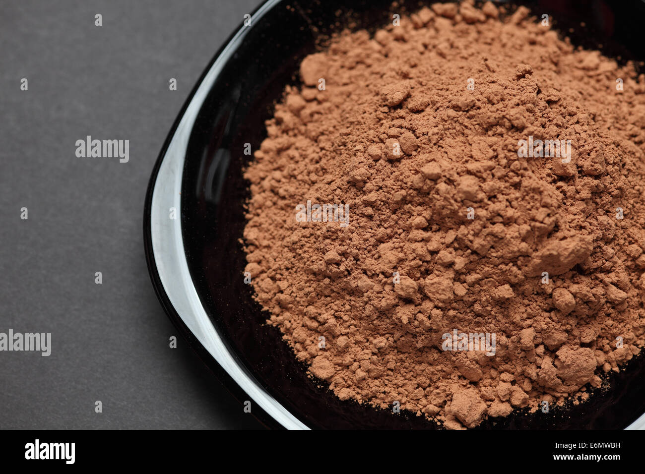 Haufen von Kakaopulver auf einer schwarzen Platte auf schwarzem Hintergrund. Closeup. Stockfoto