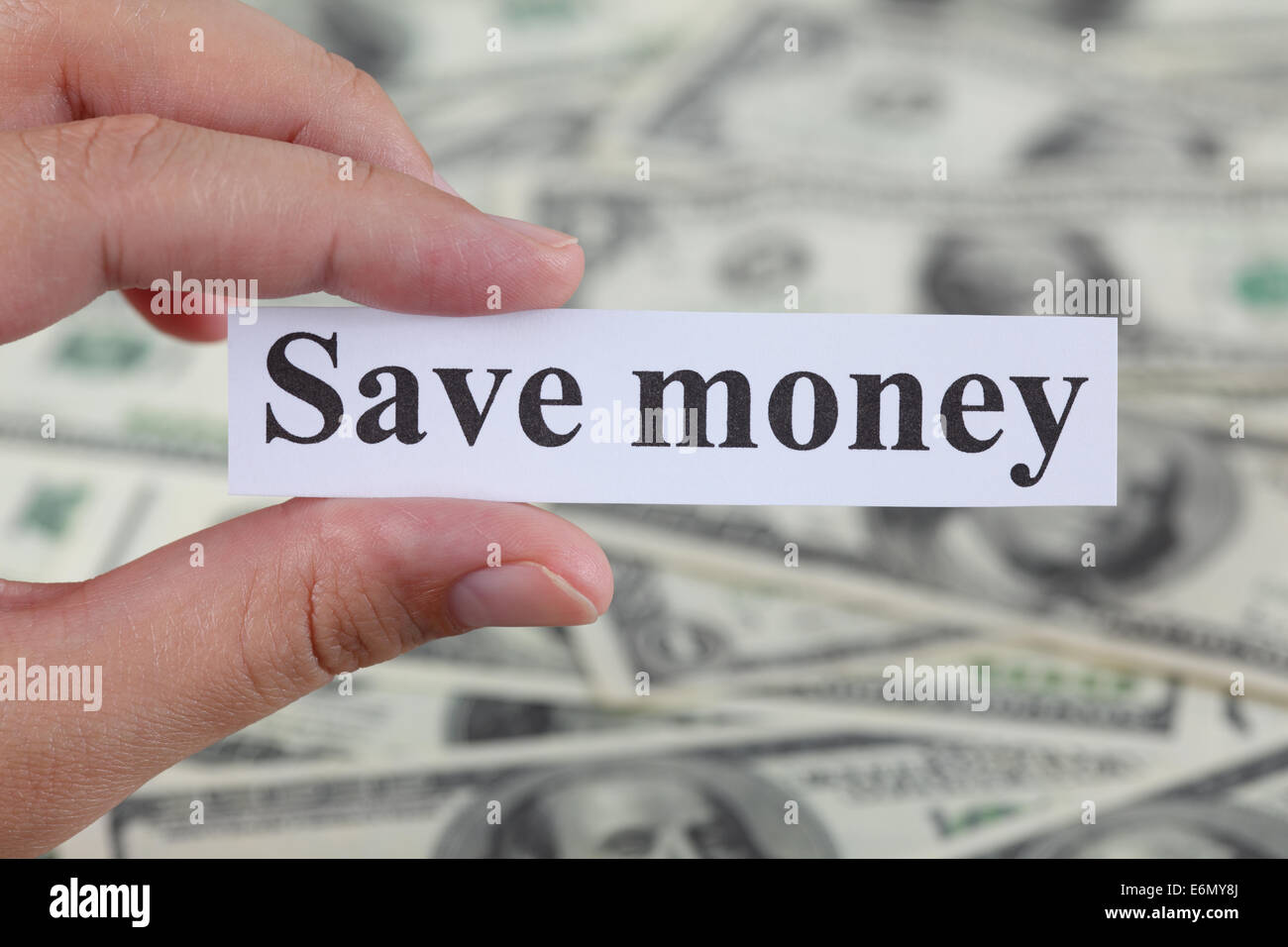 Zarte Frauenhand hält ein Stück Papier mit den Worten "Geld sparen" Dollar Bill Hintergrund. Close-up. Stockfoto