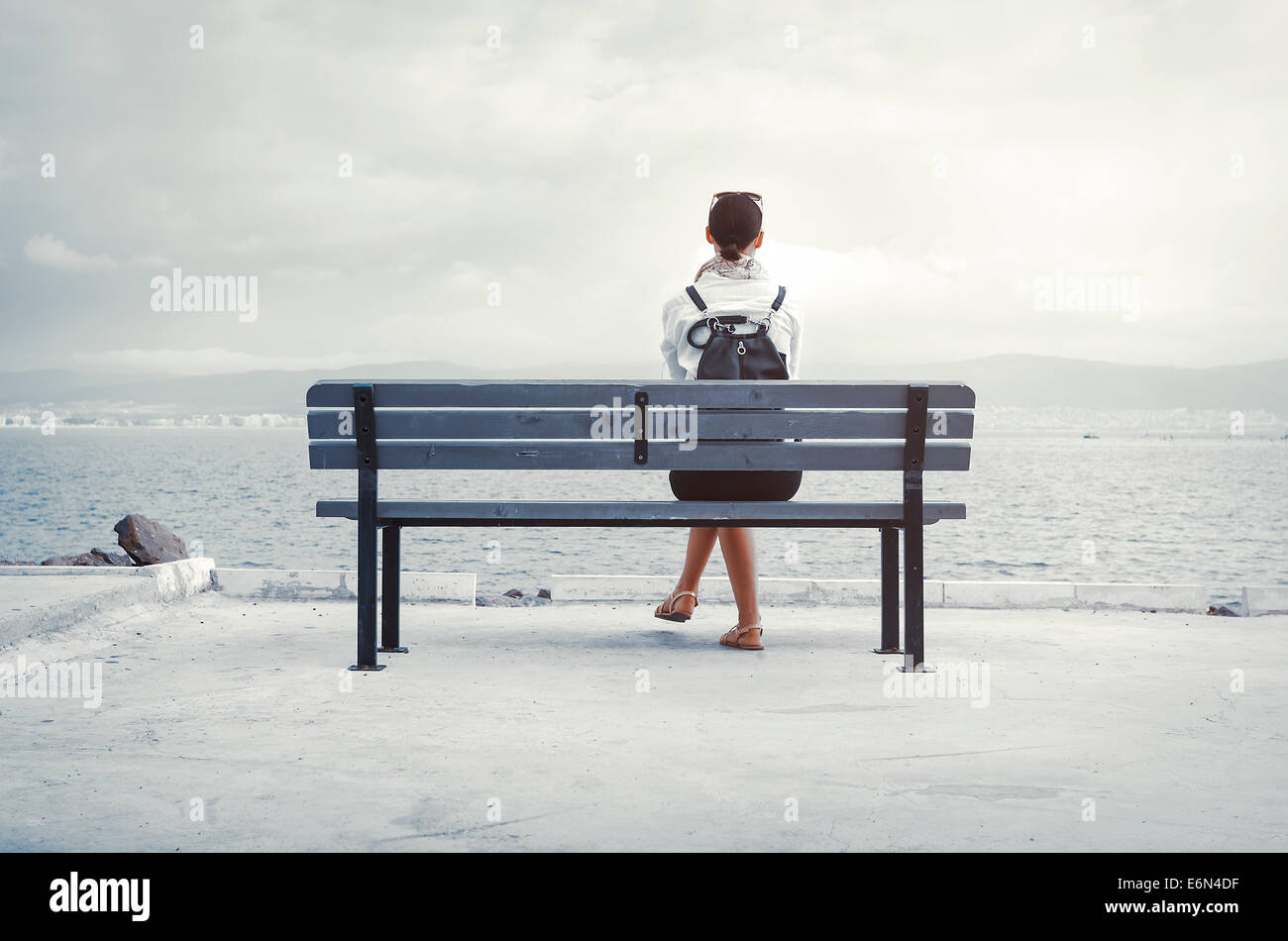 Einsame Frau sitzen auf einer Bank am Meer Stockfoto