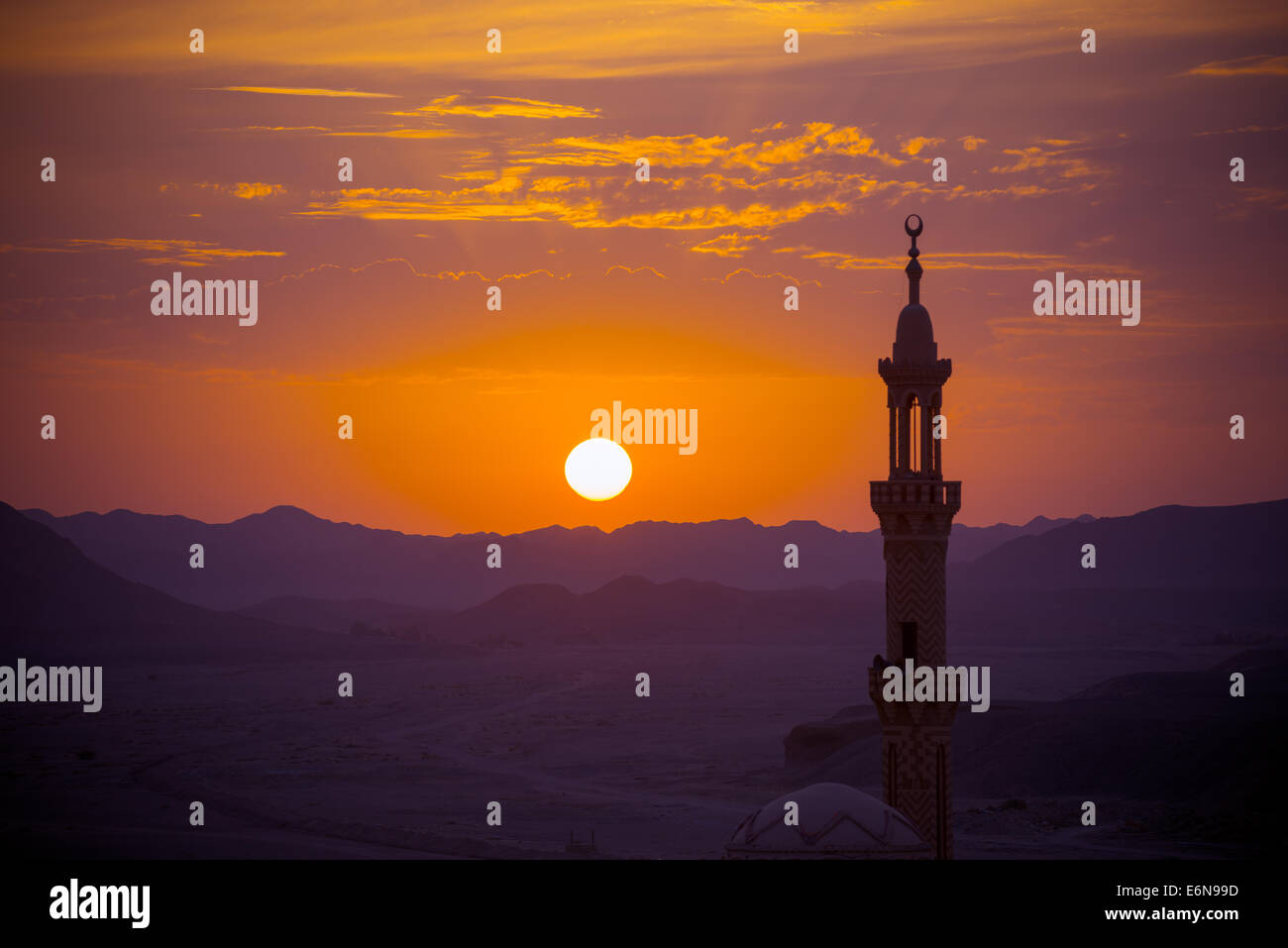 Sonnenuntergang über der Wüste mit Moschee im Vordergrund. Ferne Berge im Fokus Stockfoto