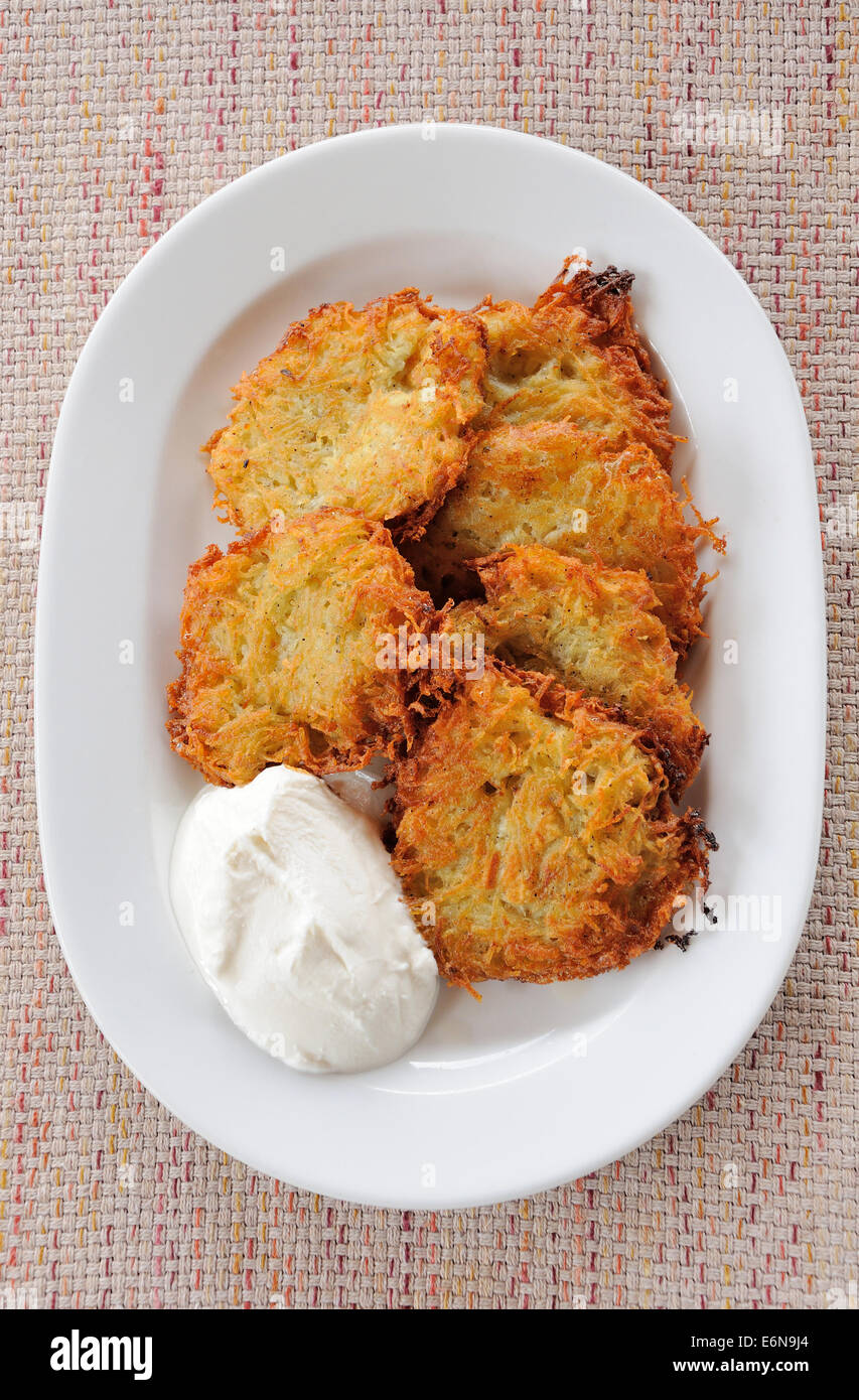 Kartoffelpuffer mit saurer Sahne auf weißen Teller Stockfoto