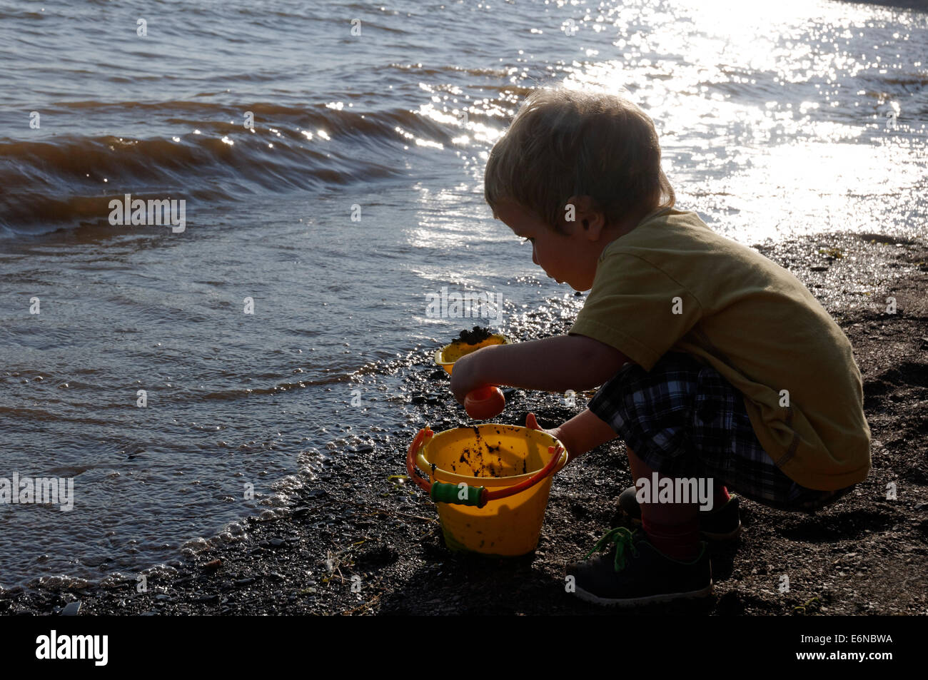 Ein Junge spielt mit einem Eimer und Spaten am Strand Plage Jacques Cartier, Quebec auf dem St Lawrence Shoreline Stockfoto