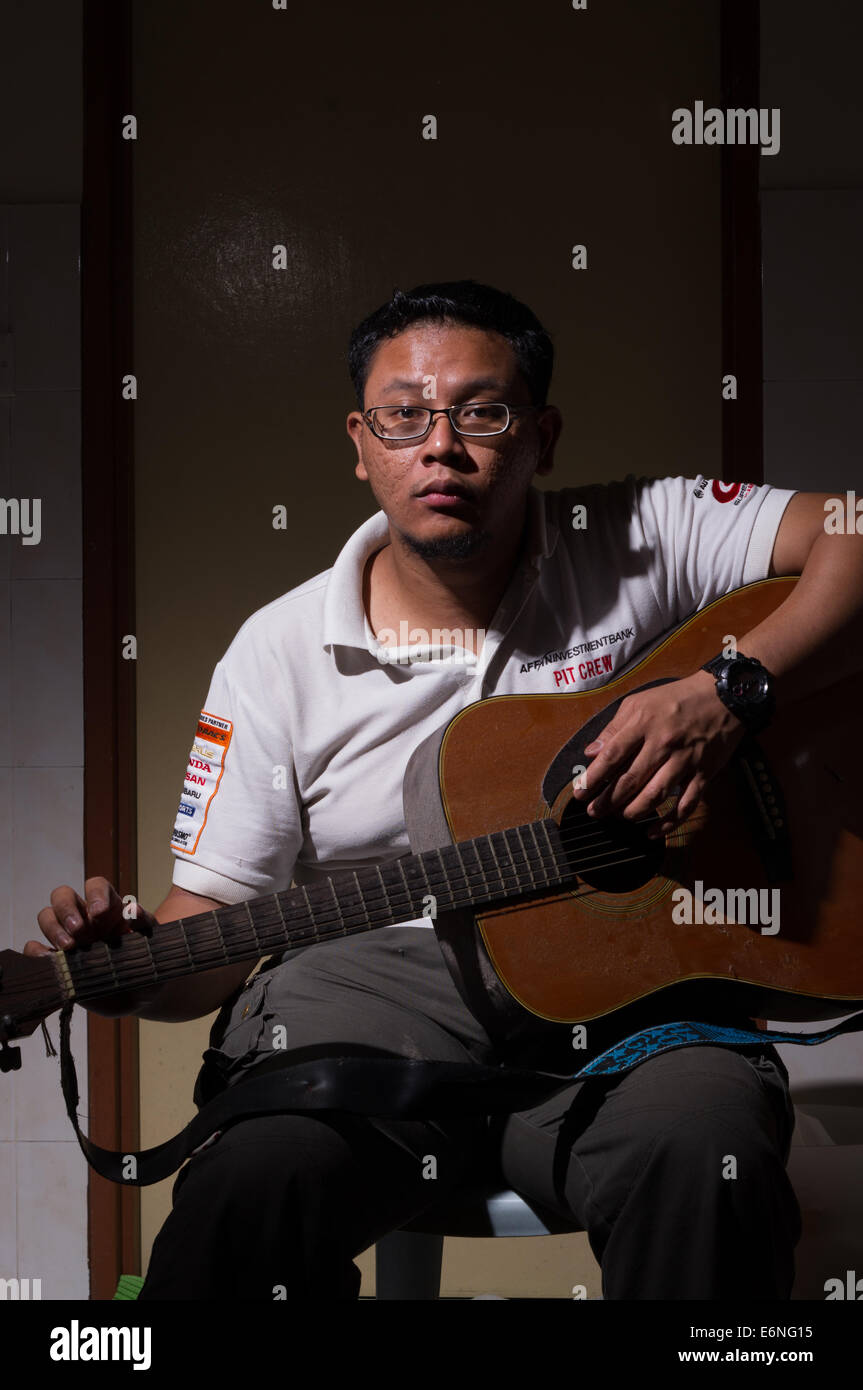 Malaiische junge Erwachsene Gitarre spielen Stockfoto