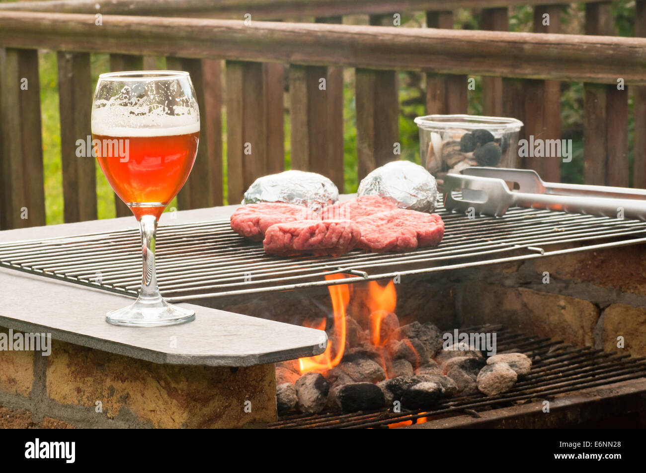 Burger auf einem brennenden Grill Grill mit einer Klasse von Craft Beer Stockfoto