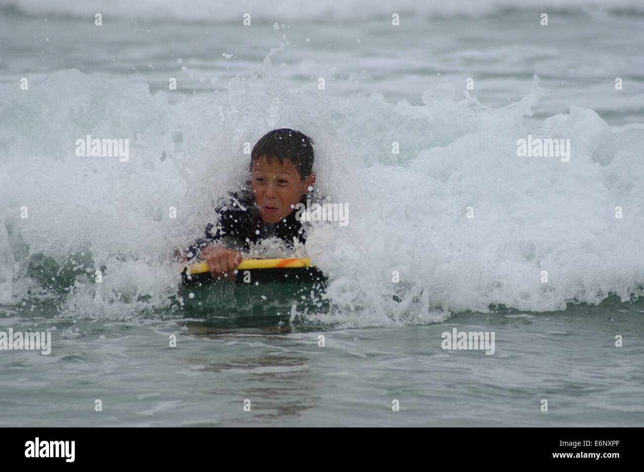 Junge männliche Jugendliche Surfen auf einem Bodyboard im Meer mit einer Welle bricht über ihn Stockfoto