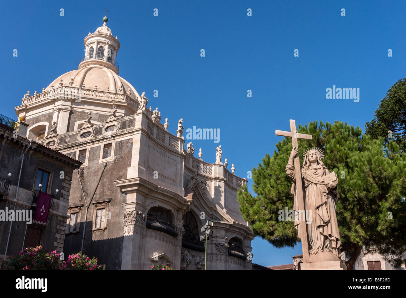 Statue der Heiligen Agatha von Sizilien hält ein Kreuz mit Duomo di Catania im Hintergrund Stockfoto
