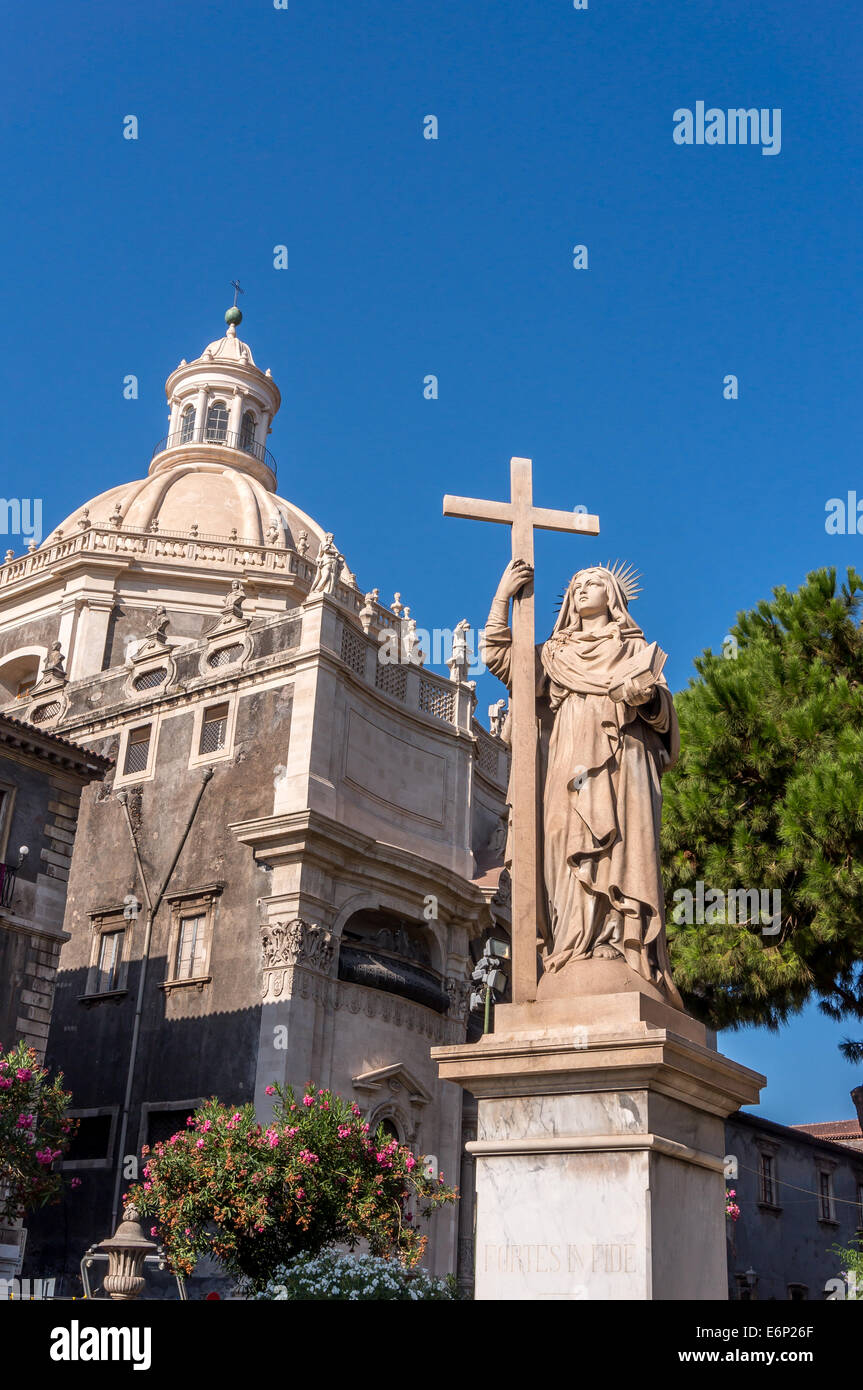 Statue der Heiligen Agatha von Sizilien hält ein Kreuz mit Duomo di Catania im Hintergrund Stockfoto