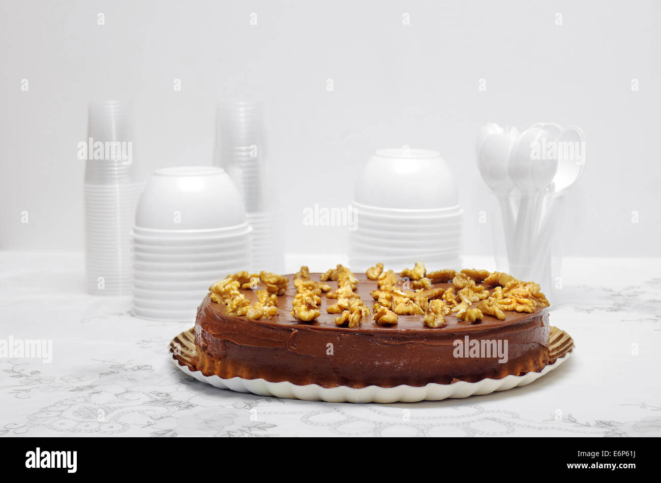 Schokoladenkuchen mit Nüssen auf einem Tisch mit einer weißen Tischdecke und weiße Tassen und Schalen Stockfoto