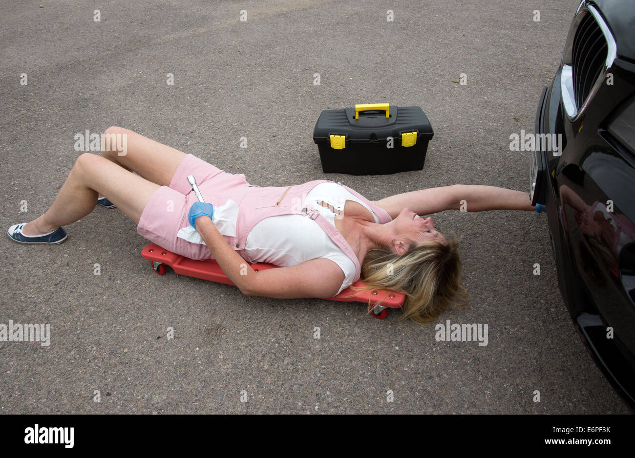 Arbeiten am Auto weibliche Kfz-Mechaniker ein Crawler Zugriff unter einem Auto auflegen Stockfoto