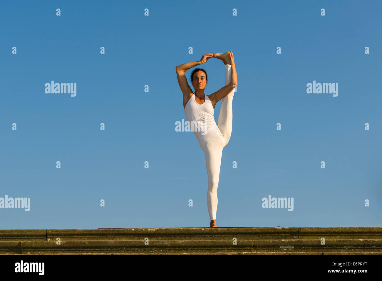 Junge Frau praktizieren Hatha Yoga im Freien, hob zeigen die Pose Utthita Hasta Pandangusthasana, die Hand zur Großzehe-pose Stockfoto