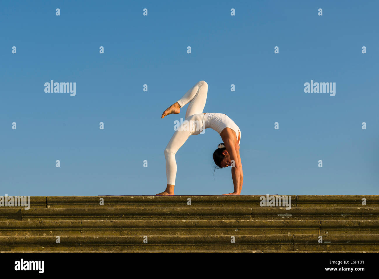 Junge Frau Hatha Yoga im Freien praktizieren, zeigt die Pose Chakrasana, Urdhva Dhanurasana, Rad-Pose Stockfoto