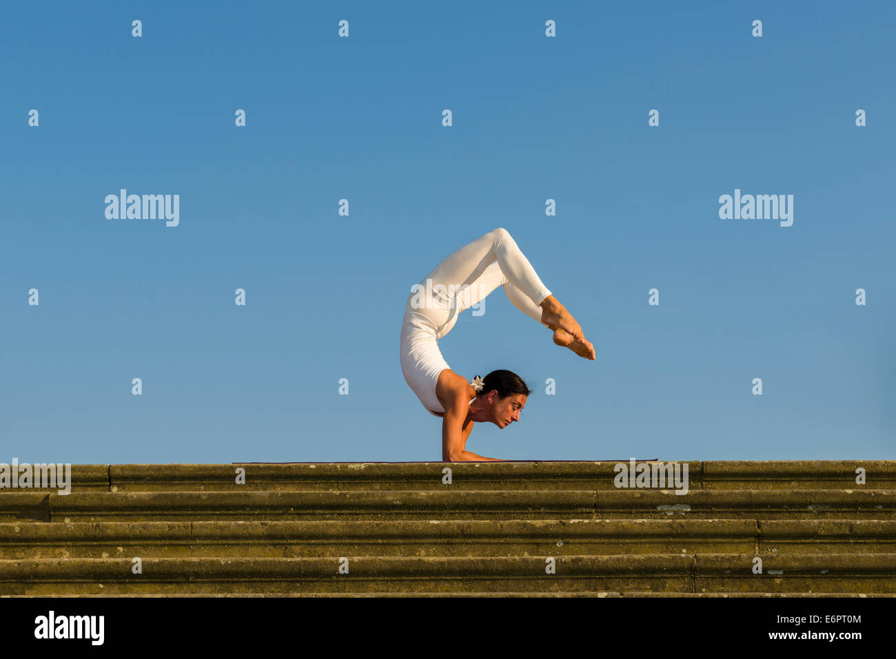 Junge Frau Hatha Yoga im Freien praktizieren, zeigt die Pose Vrischikasana, Scorpion pose Stockfoto