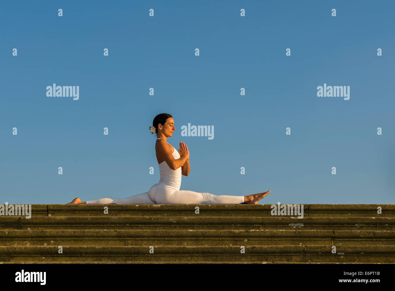 Junge Frau praktizieren Hatha Yoga im Freien, zeigen die Pose Anjaneyasana, Hanumanasana, Split Stockfoto