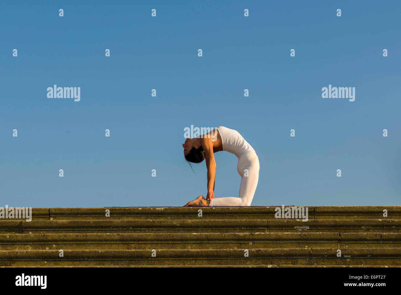 Junge Frau Hatha Yoga im Freien praktizieren, zeigt die Pose Ushtrasana, Kamel-pose Stockfoto