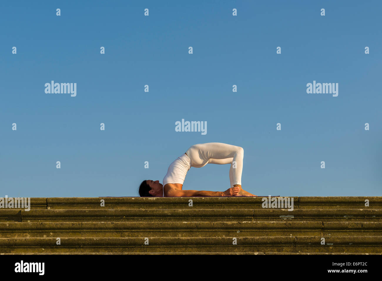 Junge Frau Hatha Yoga im Freien praktizieren, zeigt die Pose Variation der Halasana, Supta Konasana, Variation der Pflug Stockfoto