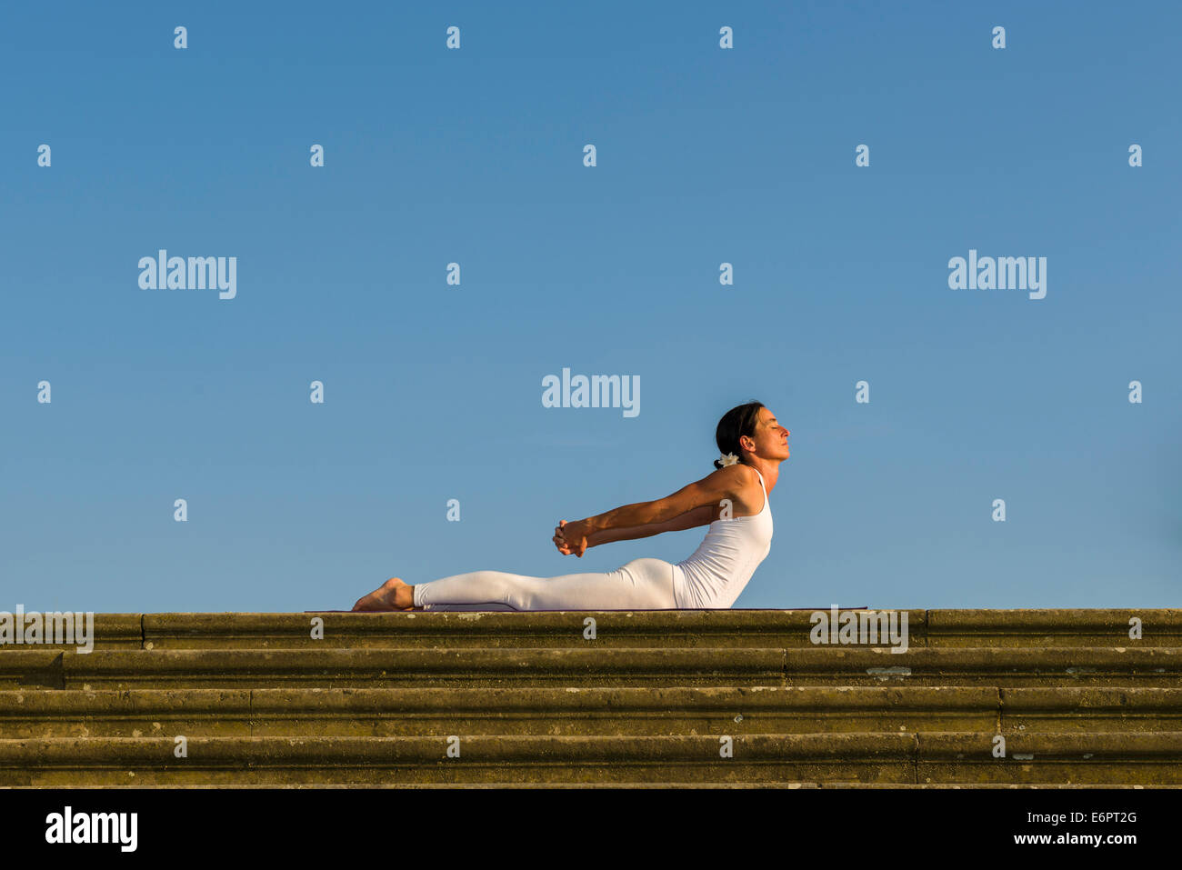 Junge Frau Hatha Yoga im Freien praktizieren, zeigt die Pose Bhujangasana, Kobra-pose Stockfoto