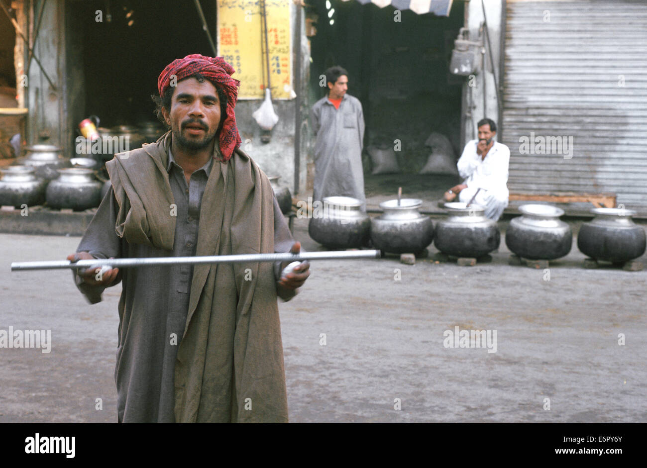 Armen muslimischen Mann, der betet vor einem Mausoleum - Moschee. Hinter ihm, Kessel mit Essen für die Armen (Pakistan) Stockfoto