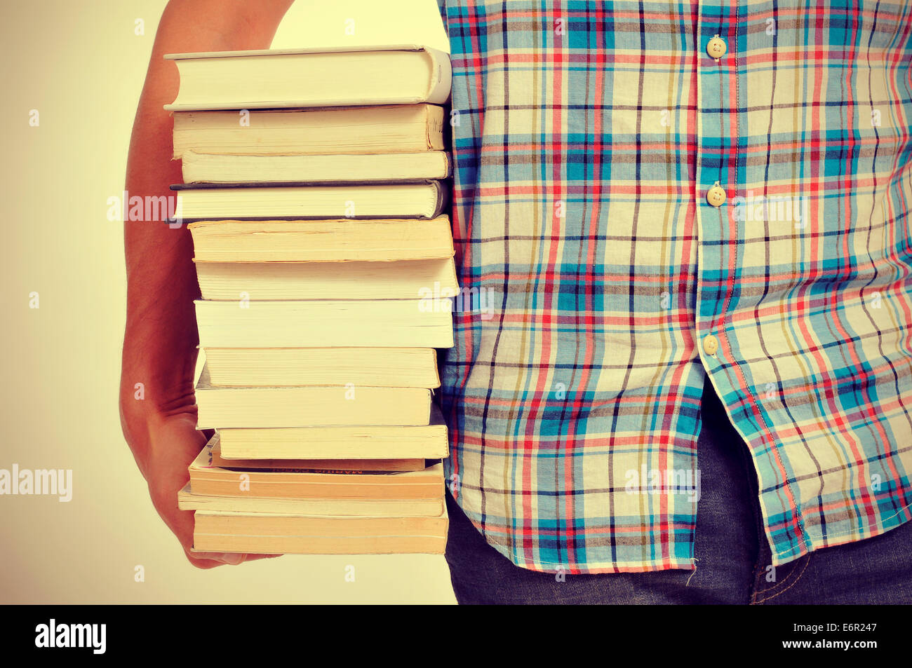 Nahaufnahme eines jungen Mannes mit einem Stapel Bücher mit einem Filtereffekt Stockfoto