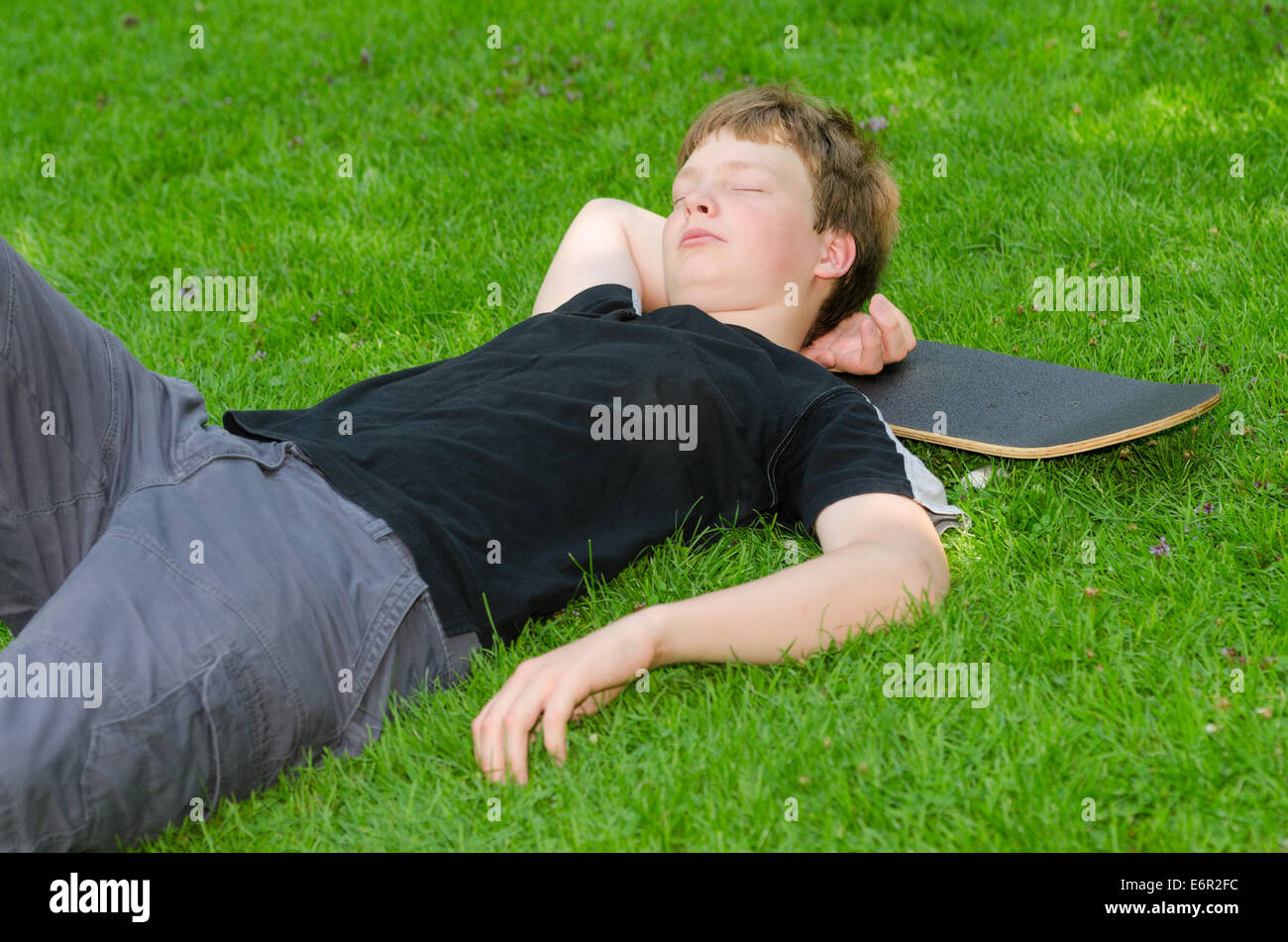 Teenager mit Skate ruht oder schläft auf dem Rasen nach aktiven skateboarding Stockfoto