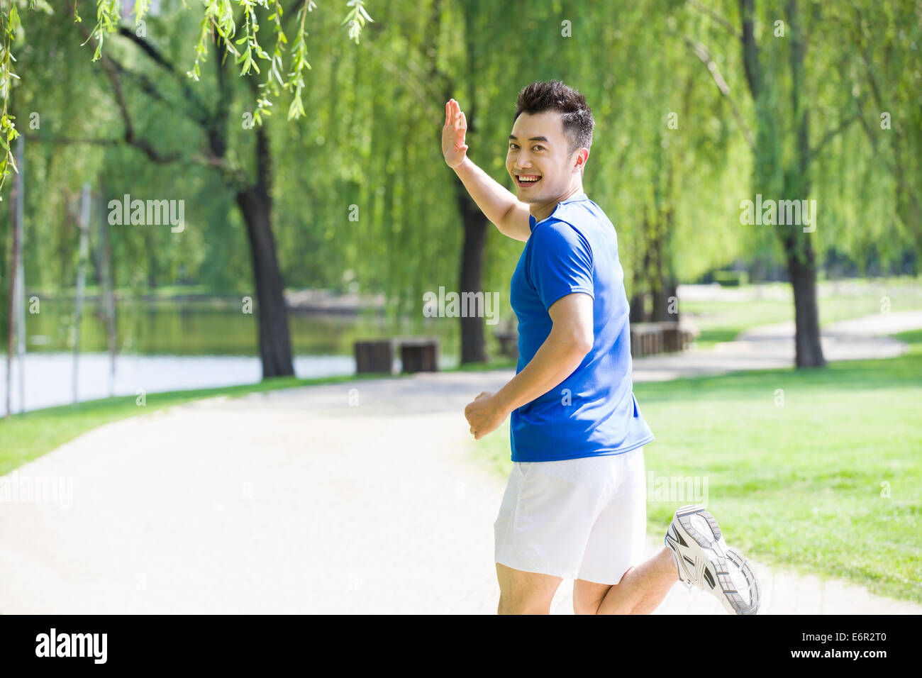 Junger Mann Joggen und winken im park Stockfoto