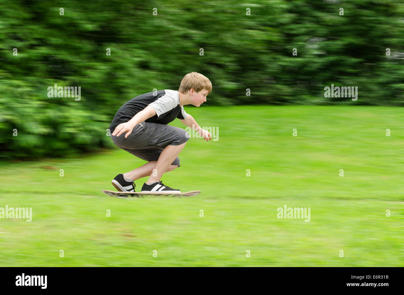 Junge Teen Kerl schnell fährt Skateboard im Park. Slow-Shutter Foto in Aktion mit unscharfen Bäumen und Rasen Hintergrund und Kopie-sp Stockfoto