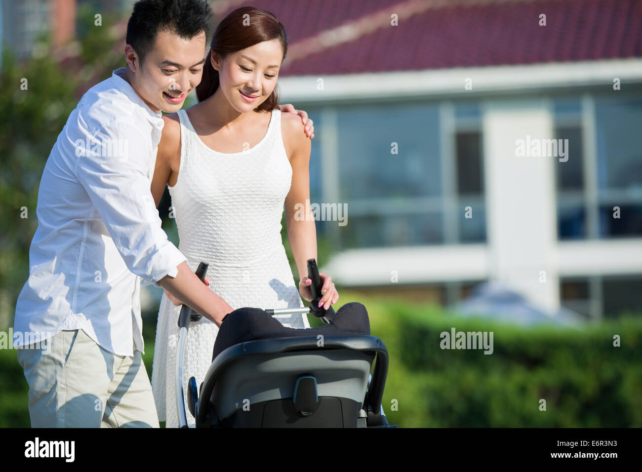 Junges Paar mit ihrem Baby im Kinderwagen spazieren Stockfoto