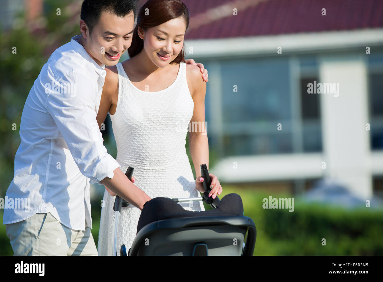 Junges Paar mit ihrem Baby im Kinderwagen spazieren Stockfoto