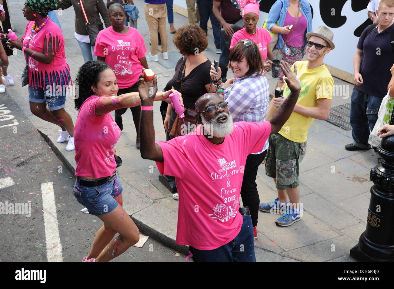 Senoir Black Man Notting Hill Karneval mit rosa Farbe auf ihn gegossen Stockfoto