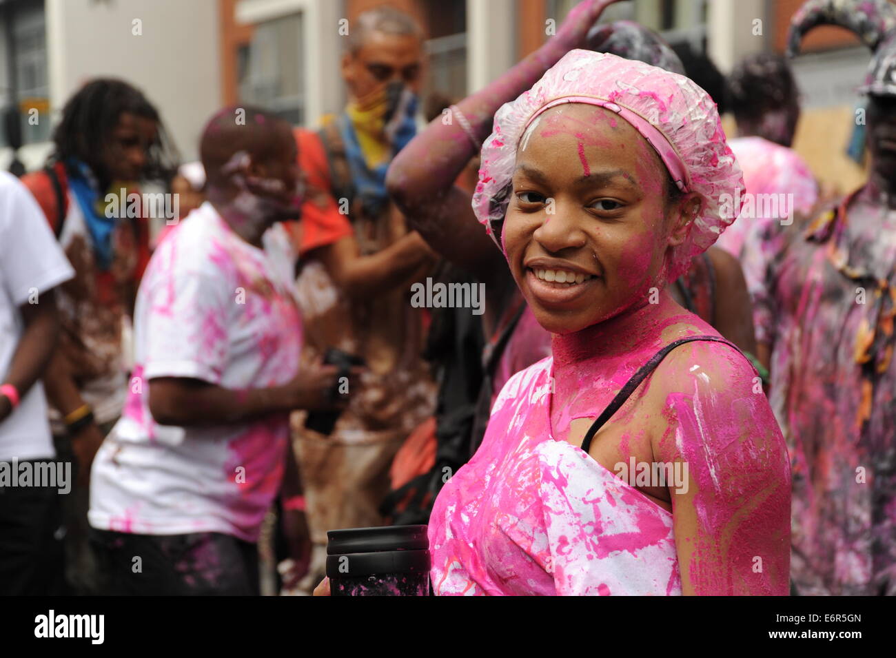 Young Black Women in Notting Hill Carnival in rosa Farbe in die Kamera Lächeln bedeckt Stockfoto