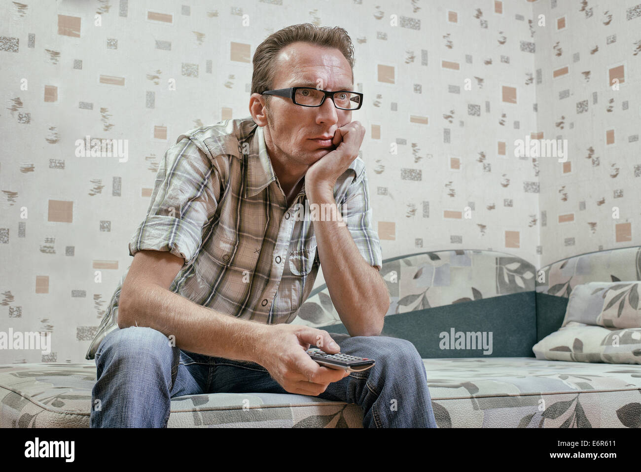Traurige und ernste Mann mit Fernbedienung in seiner Hand Uhr Fußball Mathematik oder Nachrichten im Fernsehen ausgestrahlt. Stockfoto