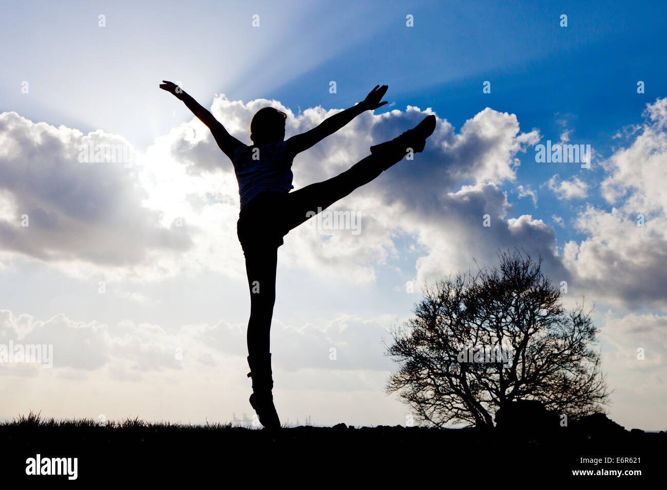 Silhouette einer jungen Frau, die unter freiem Himmel tanzen. Stockfoto