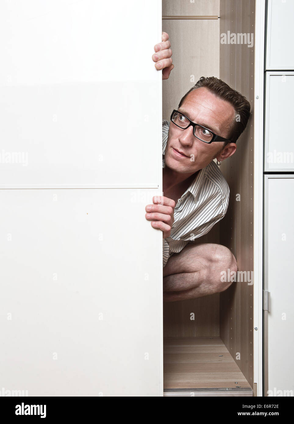 Neugierigen Mann versteckt im inneren weißen Schrank. Stockfoto