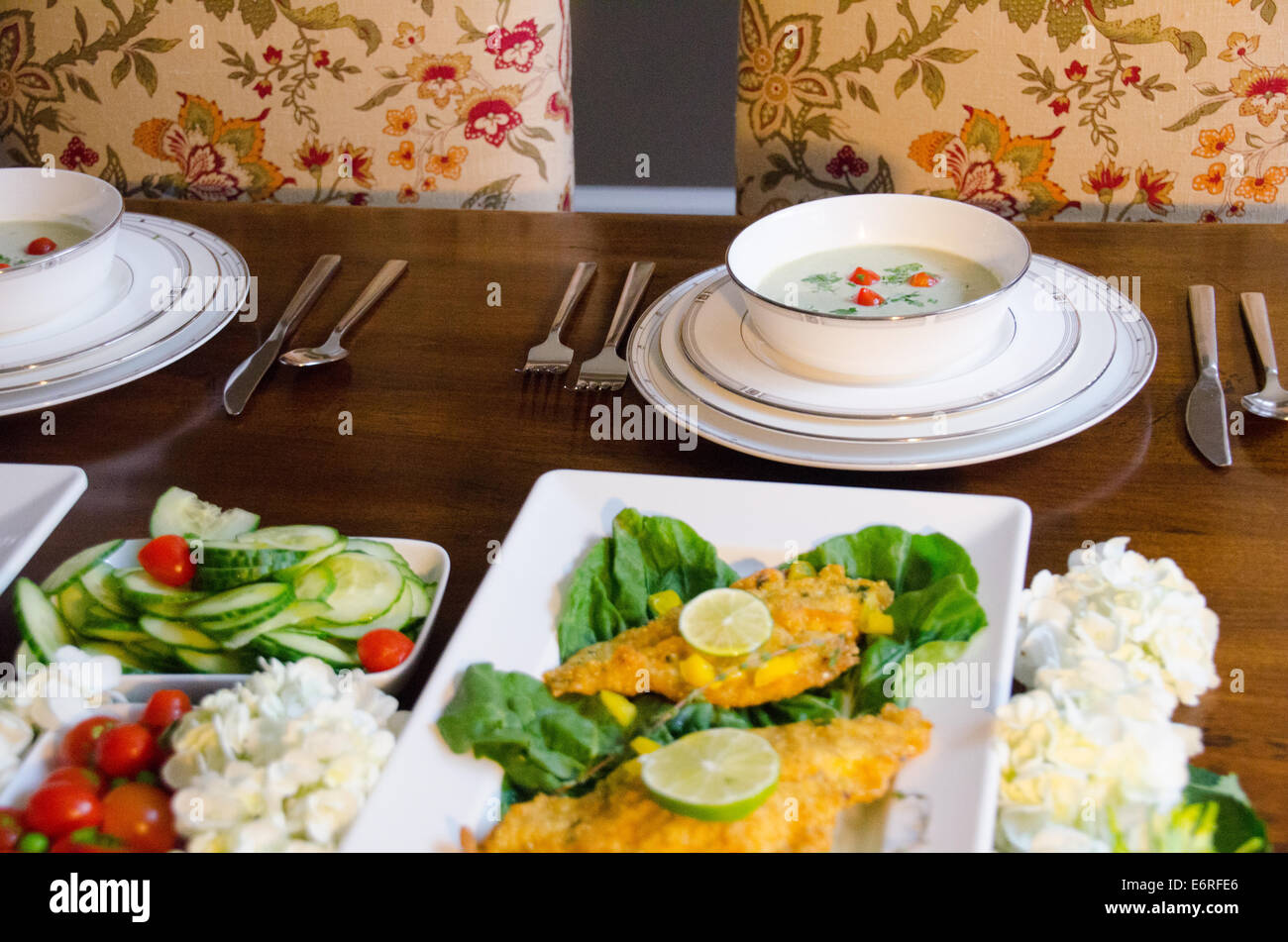 Familienessen mit Blumendruck Stühlen und Weißware Gerichte Stockfoto