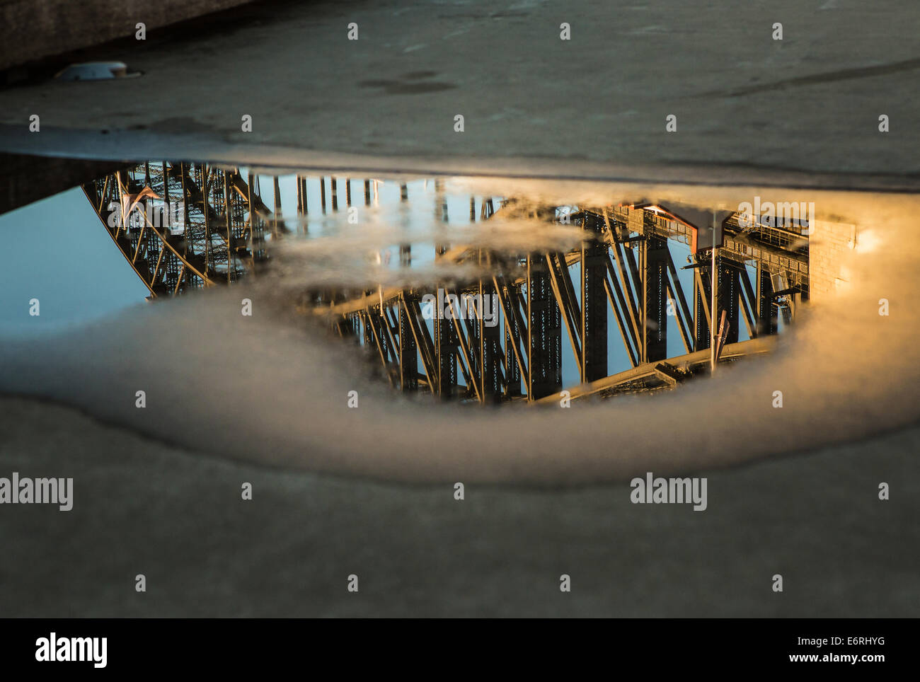 Die Sydney Harbour Bridge spiegelt sich in einer Pfütze nach einem schweren Regen. Stockfoto