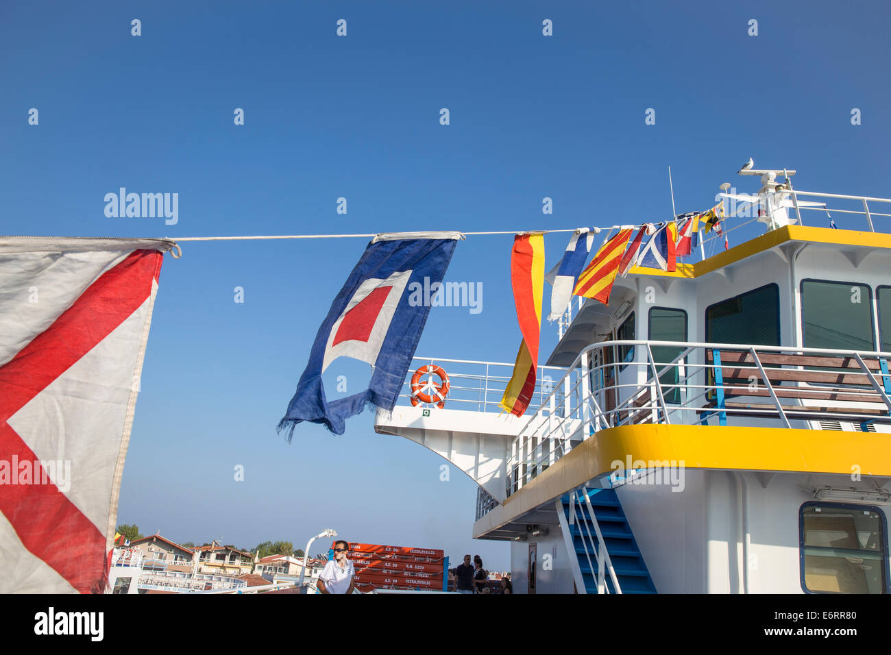 Fahnen und Passagiere an Bord einer Fähre verlassen den Hafen von Keramoti in Griechenland Stockfoto