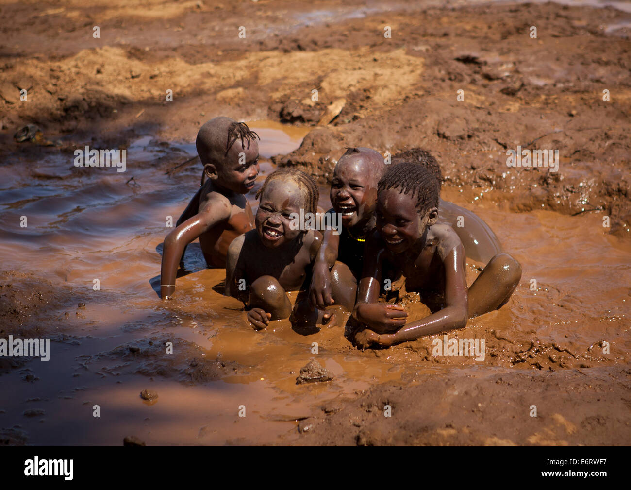 Nyangatom Kinder spielen im schlammigen Wasser, Kangate, Omo-Tal, Äthiopien Stockfoto