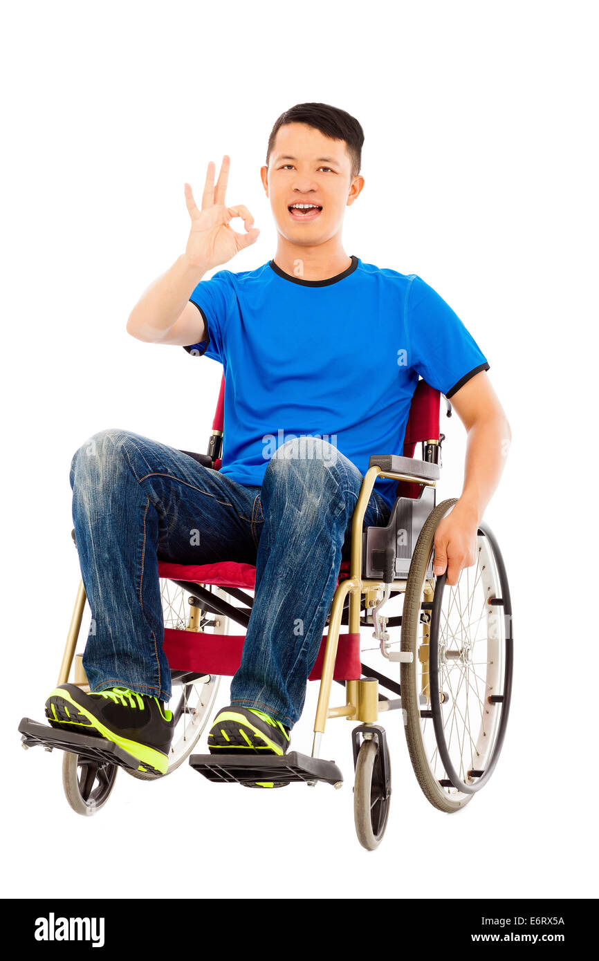 glücklich Jüngling sitzt auf einem Rollstuhl und Ordnung Geste Stockfoto